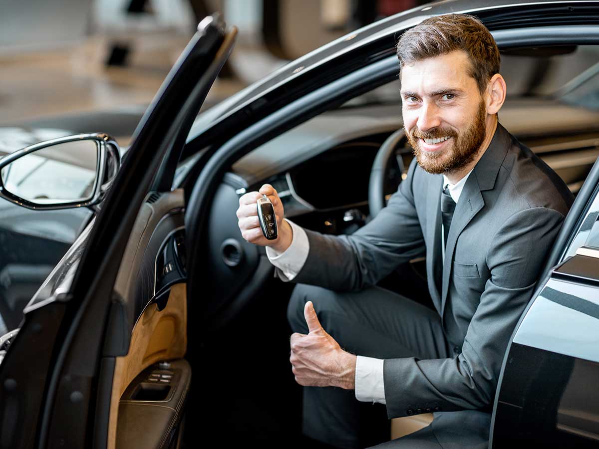 Un homme souriant à bord de sa voiture et qui montre sa clé